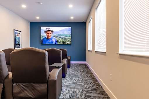 A room with a row of chairs and a television screen.