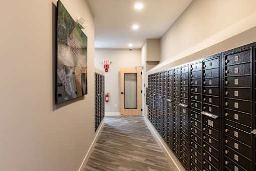 A hallway with a row of mailboxes on the right and a door at the end.