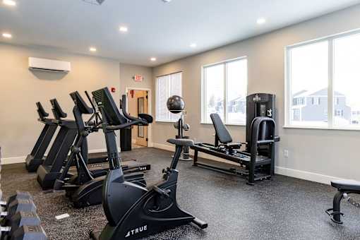 A gym with a variety of equipment including treadmills, stationary bikes, and weight machines.