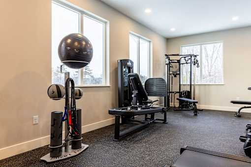 A home gym with a variety of equipment including a weight bench, a cable machine, and a squat rack.