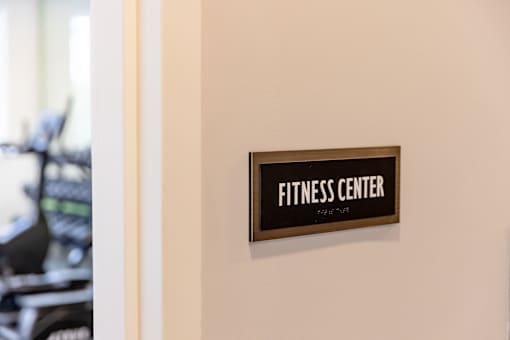 A sign that says Fitness Center is hanging on a wall.