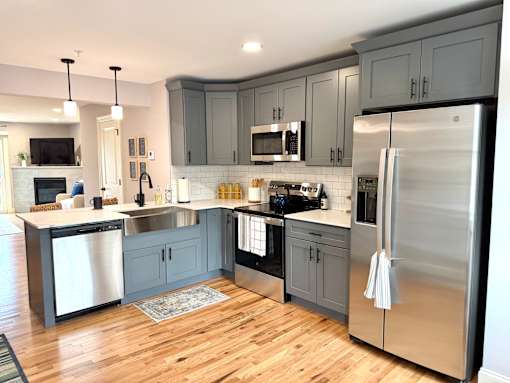 A modern kitchen with wooden floors and stainless steel appliances.