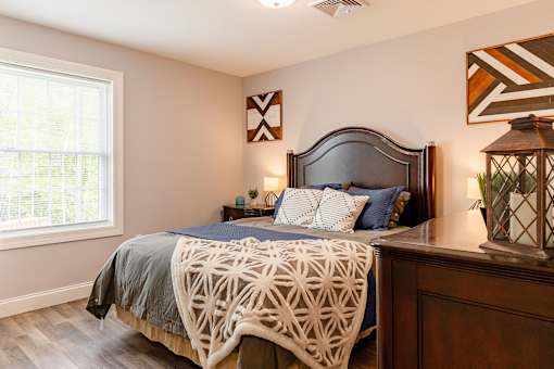 A bedroom with a bed, pillows, and a lamp.