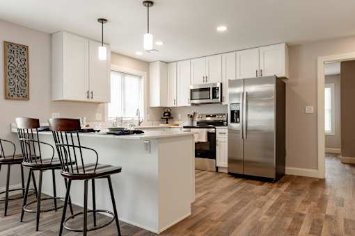 A kitchen with white cabinets and a wooden floor.