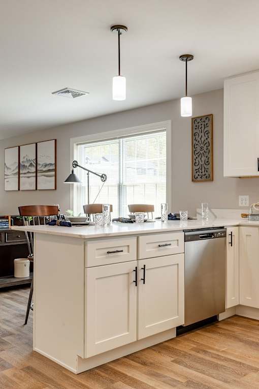 A kitchen with white cabinets and a wooden floor.