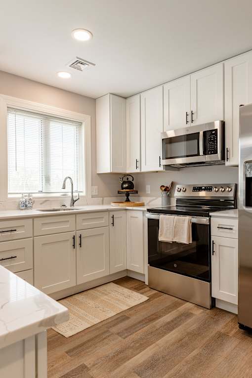 A modern kitchen with white cabinets and stainless steel appliances.