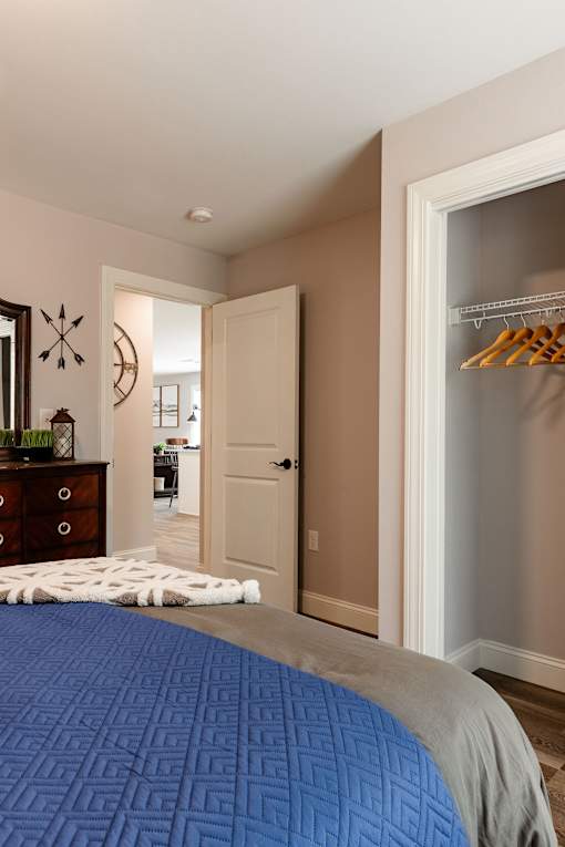 A bedroom with a blue bedspread and a wooden dresser.