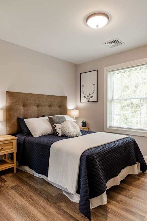 A bedroom with a large bed and a wooden nightstand.