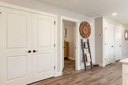 A white interior with a wooden floor and a large clock on the wall.