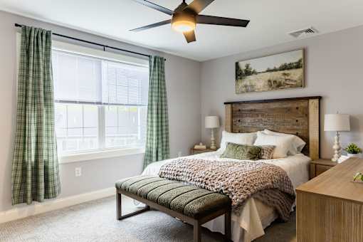 A bedroom with a bed, a bench, and a painting on the wall.