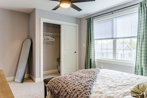 A bedroom with a bed, a window with green curtains, and a white door.