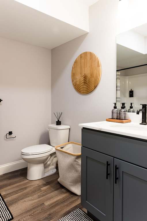 A bathroom with a toilet, sink, and a round wooden piece on the wall.