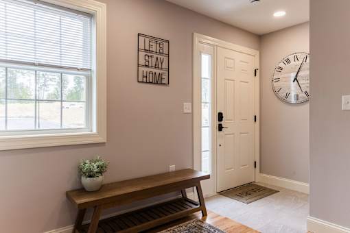 A hallway with a bench, a clock, and a sign that says "Let's Stay Home".