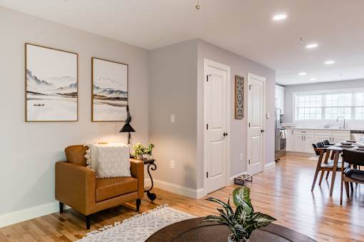 A living room with a brown chair and two landscape paintings on the wall.