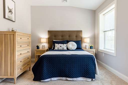 A bedroom with a large bed and a wooden dresser.