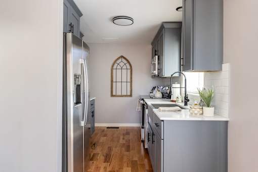 A kitchen with a stainless steel refrigerator and wooden floors.