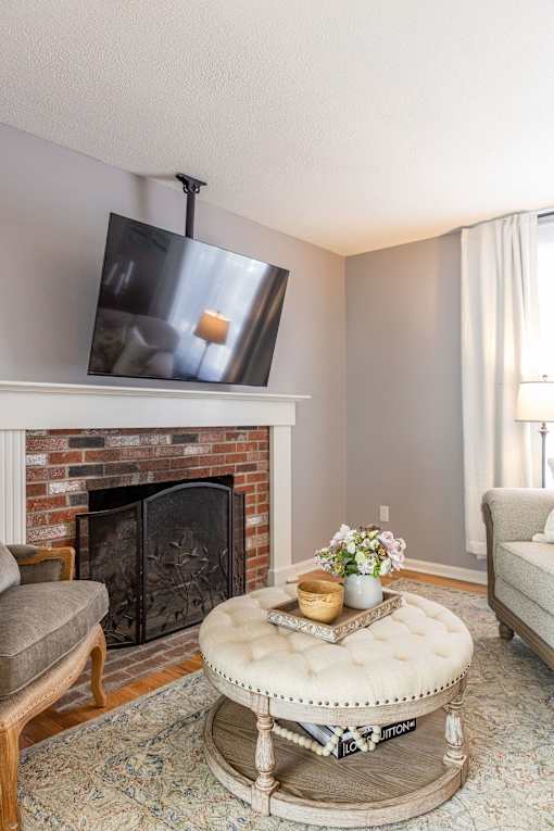 A living room with a fireplace and a flat screen TV mounted above it.