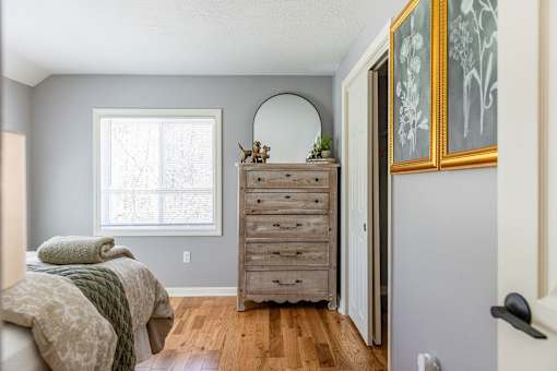 A bedroom with a bed, dresser, mirror, and two framed pictures on the wall.