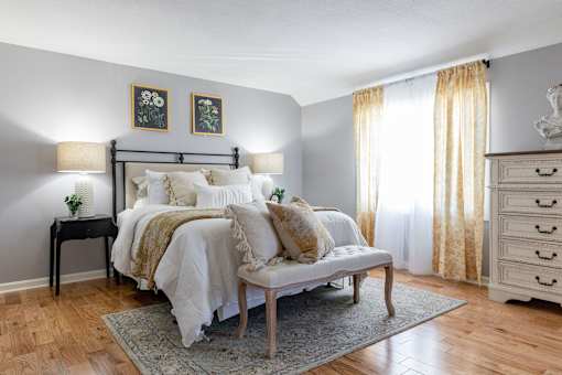 A bedroom with a bed, nightstand, and chair.