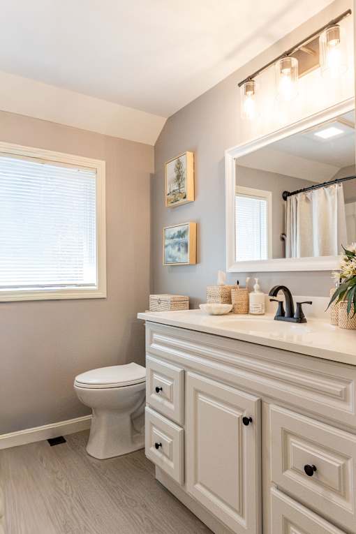 A bathroom with a toilet, sink, and a mirror.