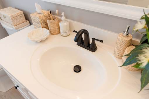 A white bathroom sink with a black faucet and a black soap.