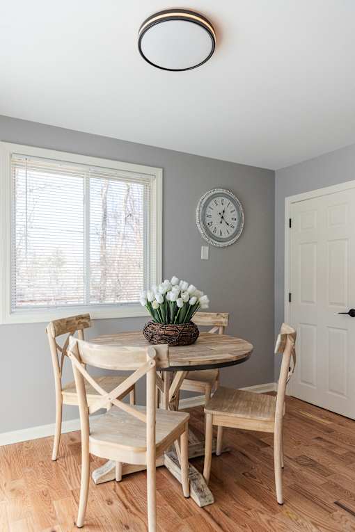 A dining room with a table set for two and a clock on the wall.