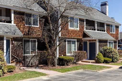 A brown house with a blue door and a tree in front.