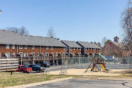 A playground with a slide and a building in the background.