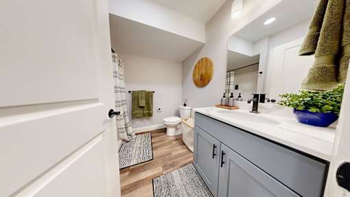 A bathroom with a white door and a grey cabinet.