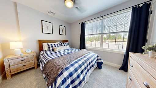 A bedroom with a bed, nightstand, and window.