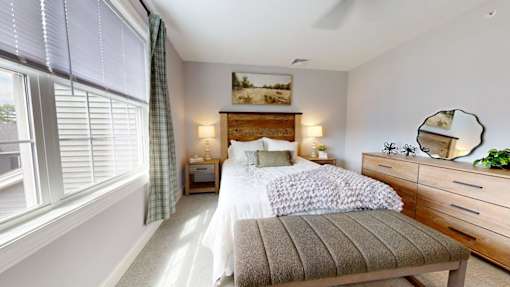 A well-lit bedroom with a large bed and a window with blinds.
