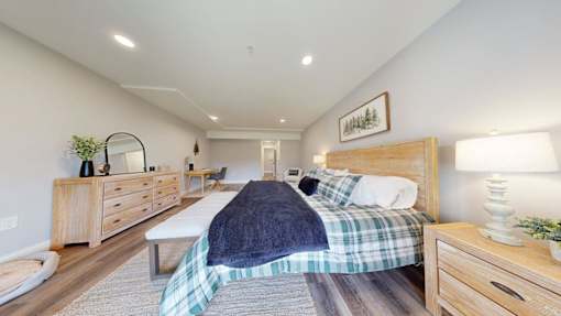 A bedroom with a bed, nightstand, and dresser.
