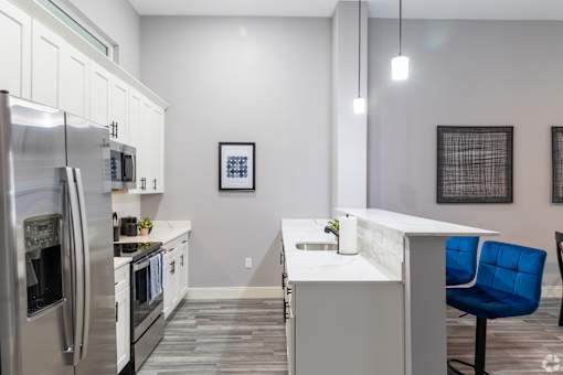 A modern kitchen with a blue chair and stainless steel appliances.