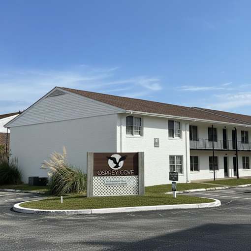 A white building with a sign that says "Osprey Cove" in front of it.