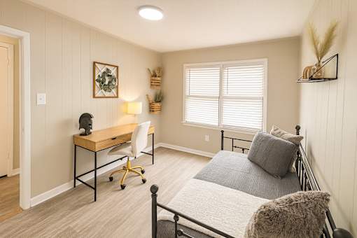 A bedroom with a bed, desk, and chair.