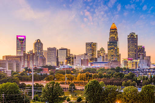 A city skyline at sunset with a prominent building in the center.