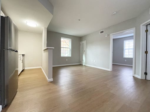 A kitchen with a refrigerator and a dining area with a table and chairs.