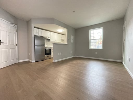 A kitchen with a refrigerator, oven, and cabinets is visible from the living room.