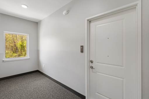 A white door is in a room with a window.