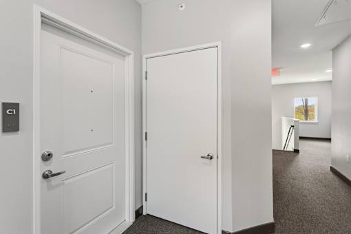 A white door with a handle and a keypad is on the left and a white door with a handle is on the right.