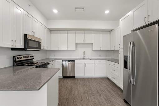 A modern kitchen with white cabinets and stainless steel appliances.