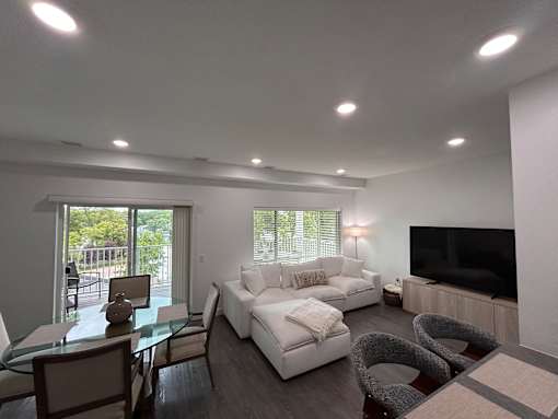 A modern living room with a glass table and white couches.
