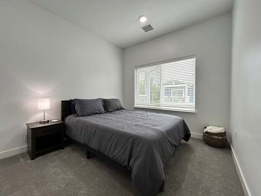 A bedroom with a bed, nightstand, and window.