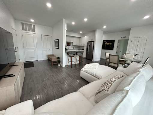 A modern living room with a white couch and a kitchen in the background.