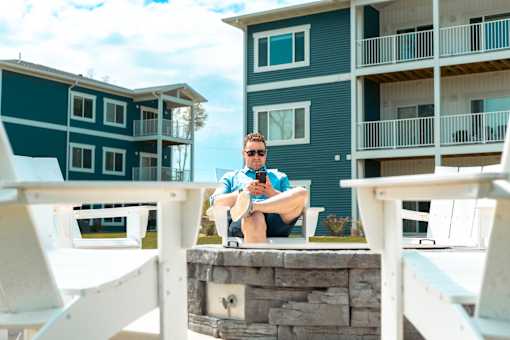 A man is sitting on a chair outside a building.