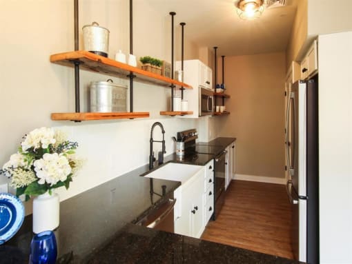 a kitchen with white cabinets and black counter tops