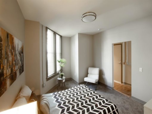 a bedroom with a bed and a chair and a window