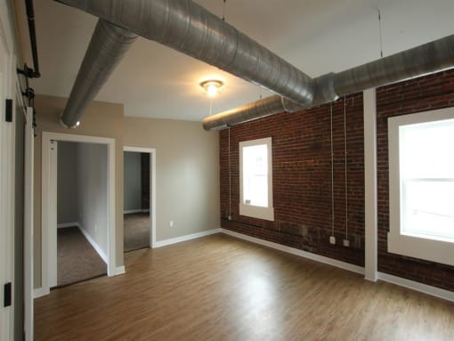 an empty living room with a brick wall and wood floors