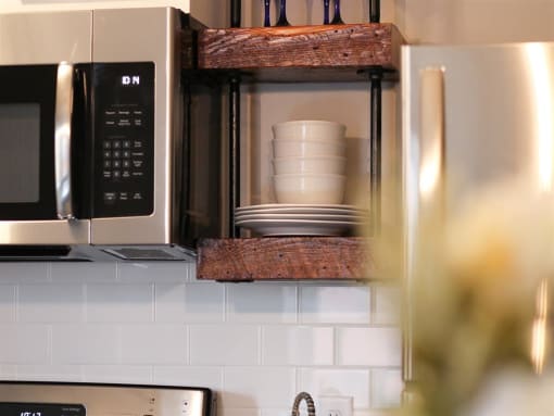 a microwave oven with a shelf with a cup and plates