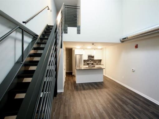 a living room with a staircase and a kitchen